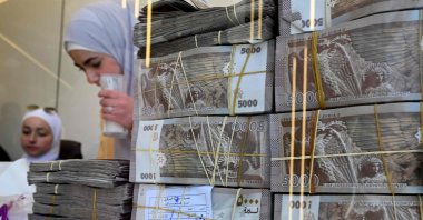 Employees stand behind stacks of local currency notes as they serve clients at an exchange shop in Damascus, Syria, April 16, 2025. (AFP Photo)