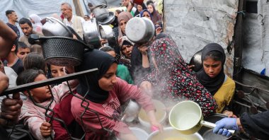 Palestinians wait to receive food cooked by a charity kitchen, in Beit Lahia, northern Gaza Strip, April 24, 2025. (Reuters Photo)