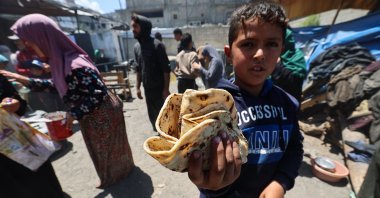 A Palestinian boy carries a portion of freshly-baked bread received from a charity kitchen run by the WFP at the Nuseirat refugee camp, central Gaza Strip, Palestine, April 26, 2025. (AFP Photo)