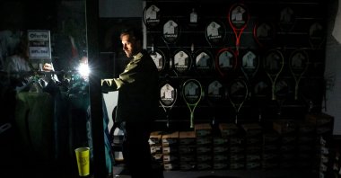 A man uses his cell phone&#039;s flashlight in a dark sports shop after the Madrid Open matches get suspended due to a power outage at the Park Manzanares, Madrid, Spain, April 28, 2025. (Reuters Photo)