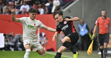 Augsburg&#039;s Mert Kömür (L) and Frankfurt&#039;s Arthur Theate challenge for the ball during the match at the WWK Arena, Augsburg, Germany,  April 20, 2025. (AP Photo)
