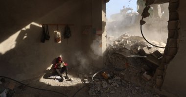 A Palestinian boy holds a book as he sits in rubble of a house, following overnight Israeli strikes, at the Nuseirat refugee camp in the central Gaza Strip, Palestine, April 29, 2025. (AFP Photo)