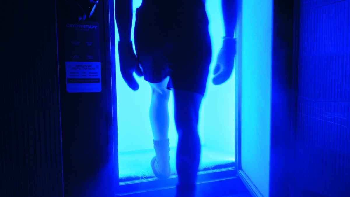 A man entering a cryotherapy cold therapy chamber in a biohacking facility.