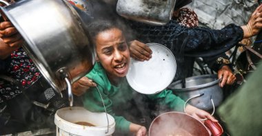 A Palestinian girl waits in long lines with a pot in hand to get food aid distributed by a charity, Jabalia Refugee Camp, northern Gaza City, Gaza, Palestine, April 28, 2025. (AA Photo)