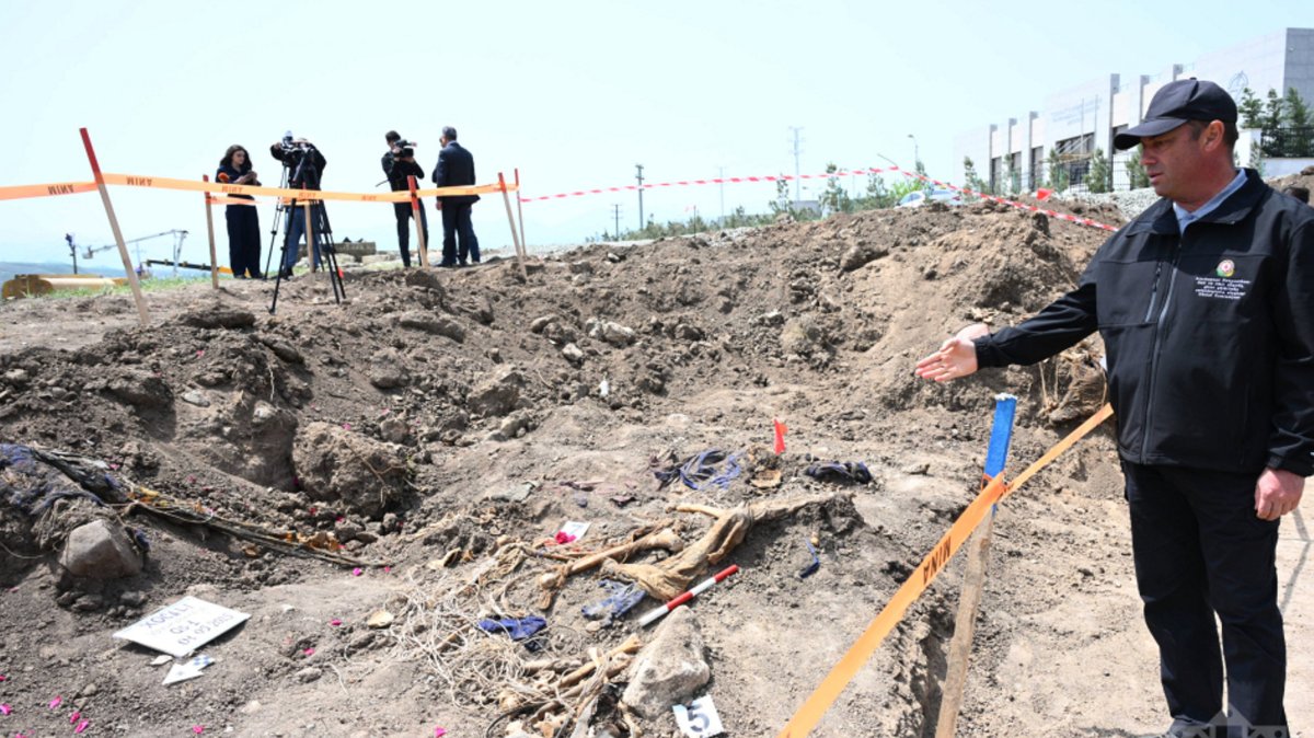 An official points at bodies uncovered in a mass grave near Shusha in the Karabakh region, Azerbaijan, May 1, 2025. (AA Photo)