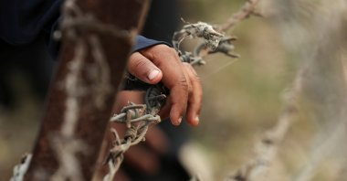 A child from Pakistan places his hand on barbed wire as he waits to go to Pakistan at the Attari-Wagah border crossing, after India revoked visas and suspended visa services to Pakistani citizens, near Amritsar, India, May 1, 2025. (Reuters Photo)