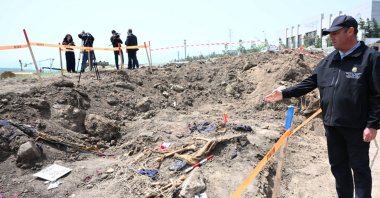 An official points at bodies uncovered in a mass grave near Shusha in the Karabakh region, Azerbaijan, May 1, 2025. (AA Photo)