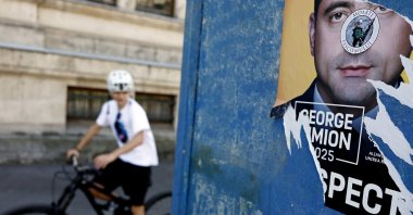 A cyclists rides past an electoral poster depicting suveranist party AUR leader George Simion, leading candidate for 2025 presidential elections, in Bucharest, Romania, May 2, 2025. (EPA Photo)