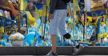 A young Ukrainian disabled veteran walks past a makeshift memorial to fallen Ukrainian soldiers, Independence Square, Kyiv, Ukraine, May 2, 2025. (EPA Photo)