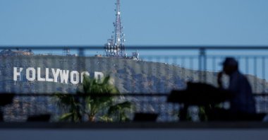 The iconic Hollywood sign is shown behind a person sitting in the shade along Hollywood Boulevard, Los Angeles, California, U.S., Feb. 25, 2025. (Reuters Photo)
