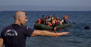 A Greek policeman gives instructions as migrants whose boat stalled at sea while crossing from Türkiye to Greece approach the shore of the island of Lesbos, Greece, Sept. 20, 2015. (AP Photo)