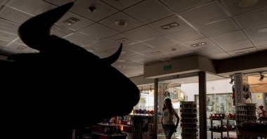 A tourist walks in a souvenir shop without lights, as a bull&#039;s head is seen in silhouette during a massive power cut affecting the entire Iberian peninsula and the south of France, Ronda, Malaga, Spain, April 28, 2025. (AFP Photo)