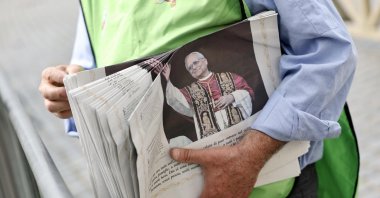 A volunteer distributes copies of the Vatican City daily newspaper "L&#039;Osservatore Romano" the day after Cardinal Robert Prevost is elected Pope Leo XIV, St. Peter&#039;s Square, Vatican, May 9, 2025. (EPA Photo)