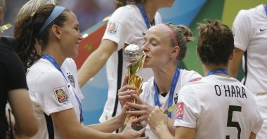 United States&#039; Becky Sauerbrunn (C)  kisses the trophy as Lauren Holiday (L) and Kelley O&#039;Hara look on after the U.S. beat Japan 5-2 in the FIFA Women&#039;s World Cup championship, Vancouver, Canada, July 5, 2015. (AP Photo)