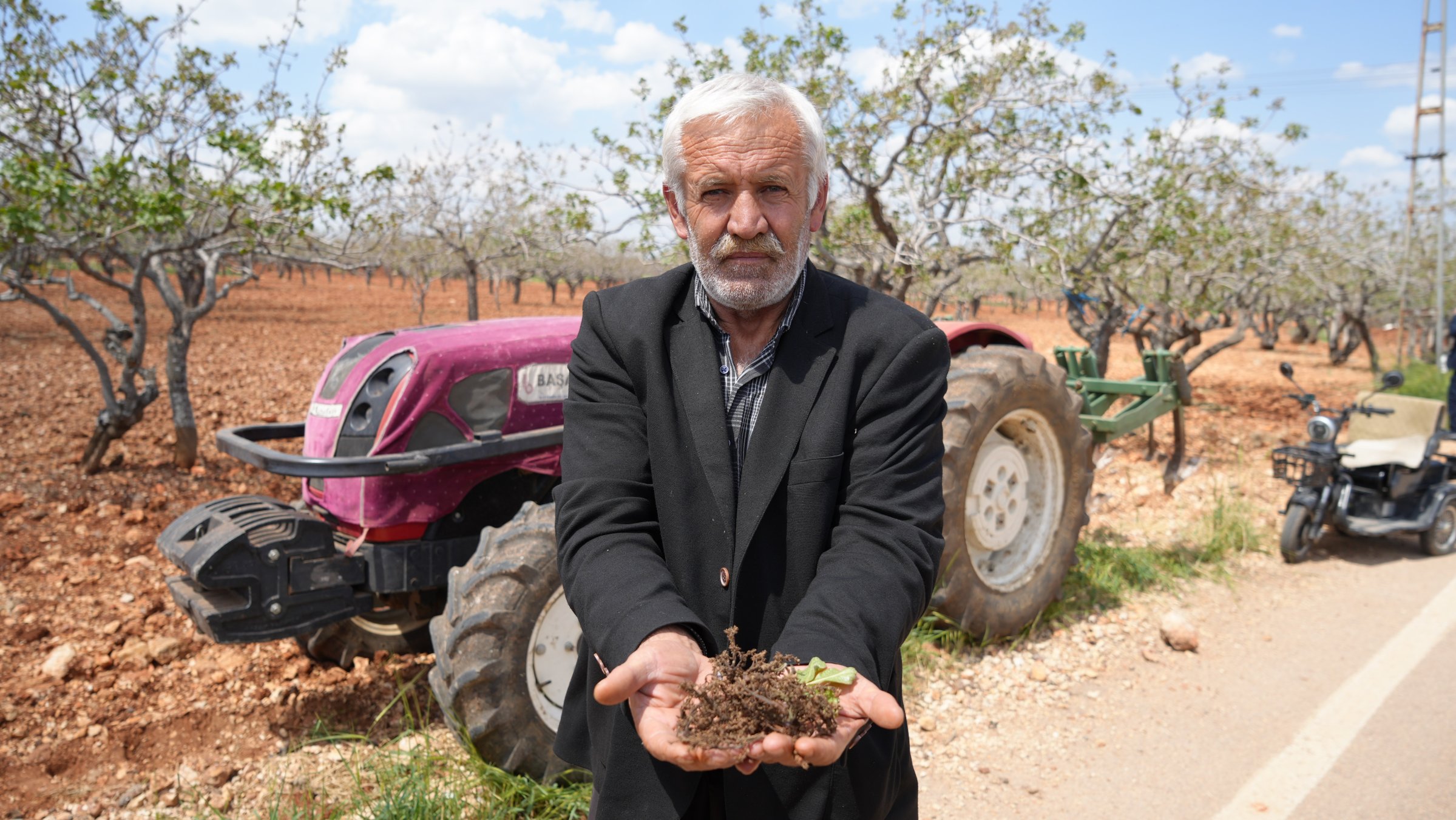A farmer stands in front of a tractor and fields affected by frost, Gaziantep, Türkiye, May 3, 2025. (İHA Photo)
