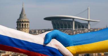 The illustration shows hands painted with the Russian (L) and Ukrainian colors, shaking with Istanbul&#039;s Galata tower and the Atatürk Olympic Stadium in the background. (Daily Sabah Illustration)