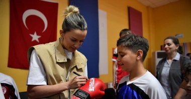 National boxer Hatice Akbaş (L) shares her experiences with Yeşilyurt Municipality Kickboxing Team athletes and signs boxing gloves during an event at the Yakınca Life and Sports Center, Malatya, Türkiye, May 2, 2025. (AA Photo)