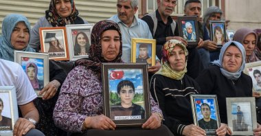 Families whose children joined the PKK terrorist group hold their images as they sit in front of the headquarters of the Equality and Democracy (DEM Party) after the PKK announced its dissolution, in Diyarbakır, southeasternTürkiye, May 12, 2025.(AFP Photo)