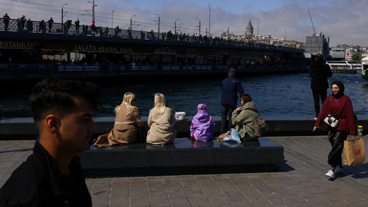 People enjoy the view of Galata Bridge and the historical Galata Tower from the shore of the Golden Horn in Eminönü neighborhood in Istanbul, Türkiye, April 23, 2025. (Reuters Photo)