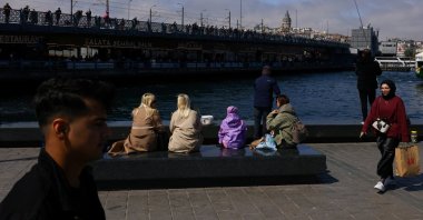 People enjoy the view of Galata Bridge and the historical Galata Tower from the shore of the Golden Horn in Eminönü neighborhood in Istanbul, Türkiye, April 23, 2025. (Reuters Photo)