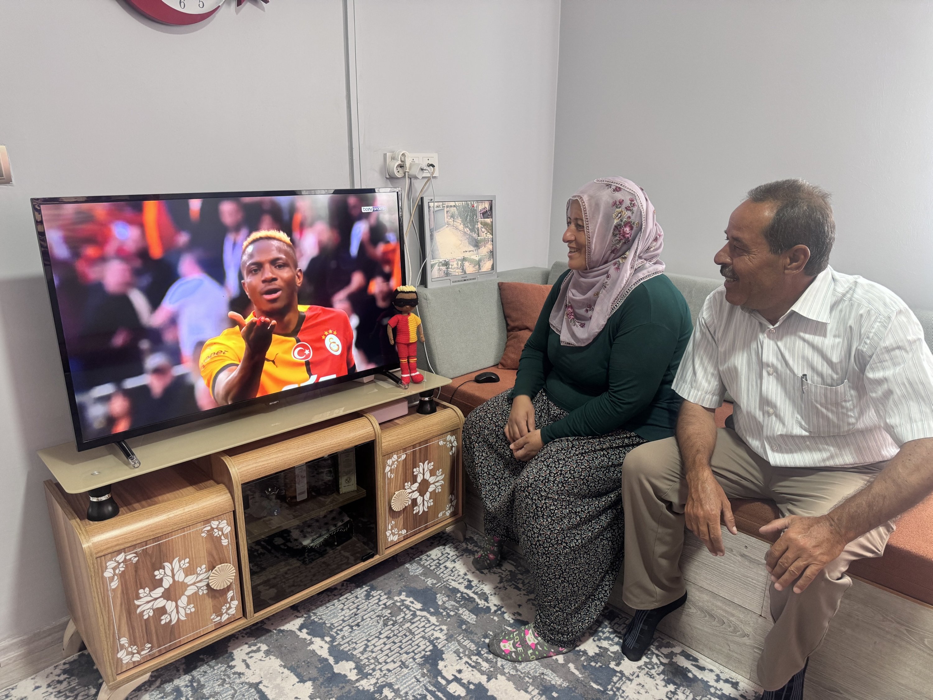 Neslihan Demir (L) and her husband watch Galatasaray's Victor Osimhen on the screen with the handmade