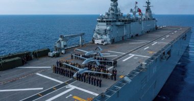 Commanders and defense industry officials pose aboard the TCG Anadolu next to Bayraktar TB3 drones, somewhere in the Mediterranean Sea, Türkiye, May 15, 2025. (DHA Photo)