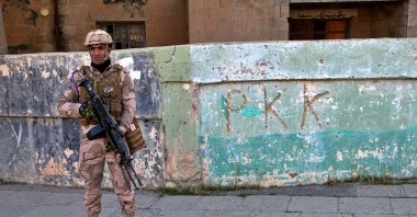 An Iraqi soldier stands next to graffiti of the PKK terrorist group, Sinjar, Iraq, Dec. 4, 2020. (AP Photo)