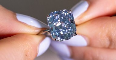 A Sotheby’s staff member holds &quot;The Mediterranean Blue,&quot; a fancy vivid blue diamond weighing 10.03 carats, estimated to reach 20 million Swiss francs during an auction preview, Geneva, Switzerland, May 8, 2025. (Reuters Photo)