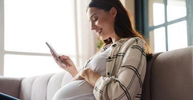 A pregnant woman uses her smartphone to access health information. (Shutterstock Photo)