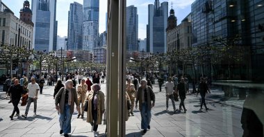 People walk on the main shopping Zeil street in front of the banking district skyline, Frankfurt am Main, western Germany, April 23, 2025. (AFP Photo)
