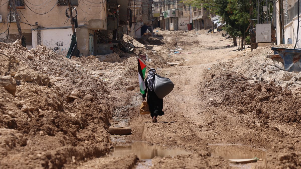 A Palestinian man walks past the main entrance of Tulkarem refugee camp in the West Bank city of Tulkarem, May 19, 2025. (EPA Photo)