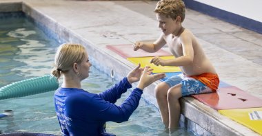 In this handout photo provided by Children&#039;s Services Council of Palm Beach County, aquatic educator Riley Taylor helps a student into the water during an autism-specific swim class at Small Fish Big Fish, West Palm Beach, Florida, U.S., April 1, 2025. (AP Photo)