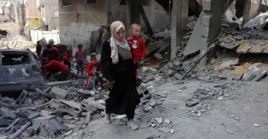 A Palestinian woman carries a toddler as she walks amid the destruction following Israeli strikes in Jabalia&#039;s Saftawi neighbourhood, northern Gaza Strip, Palestine, May 22, 2025. (AFP Photo)