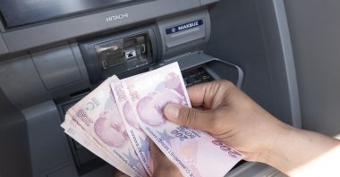 A man withdraws some Turkish lira banknotes from an ATM, Istanbul, Türkiye, June 22, 2023. (EPA Photo)