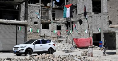  A boy walks under Palestinian flags hanging outside buildings damaged during Syria's 14-year civil war in the Yarmuk refugee camp in southern Damascus, May 22, 2025. (AFP Photo)