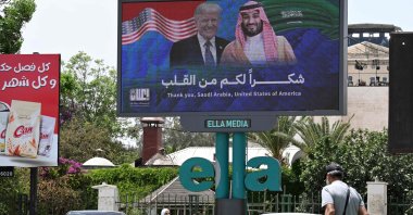 People walk past a billboard displaying portraits of Saudi Crown Prince Mohammed bin Salman and U.S. President Donald Trump with a slogan thanking Saudi Arabia and the United States, in Damascus, Syria, May 14, 2025. (AFP Photo)