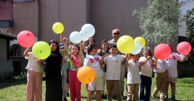 Children enjoy a festive moment with colorful balloons alongside school bus driver Salih Öztaş and his wife during their year-end garden celebration, Sakarya, Türkiye, May 25, 2025. (IHA Photo)