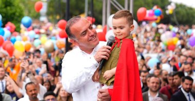Samet Demir carries his son Ali Asaf in his arms as they release a balloon together during the celebration, Istanbul, Türkiye, May 25, 2025. (DHA Photo)