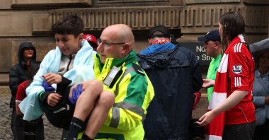 A paramedic carries a child after multiple people were hit by a car during the Liverpool Victory parade, Liverpool, U.K., May 26, 2025. (Reuters Photo)