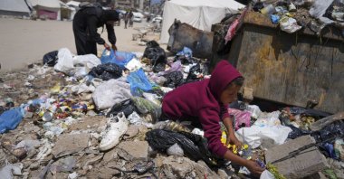 Islam Abu Taeima, a 40-year-old mother of five, left, and a boy look for some food on a pile of garbage in Gaza City, Sunday, May 25, 2025.(AP Photo/Jehad Alshrafi)