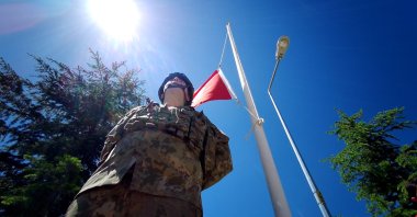 A Turkish soldier stands under a Turkish flag lowered to half-mast during a ceremony for 33 soldiers who were killed by PKK terrorists on May 24, 1993, Bingöl, eastern Türkiye, May 24, 2025. (DHA Photo)