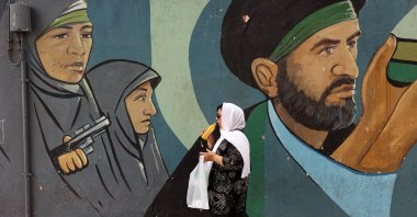An Iranian woman walks past a wall painting of IRGC soldiers in Tehran, Iran, May 21, 2025. (EPA Photo)