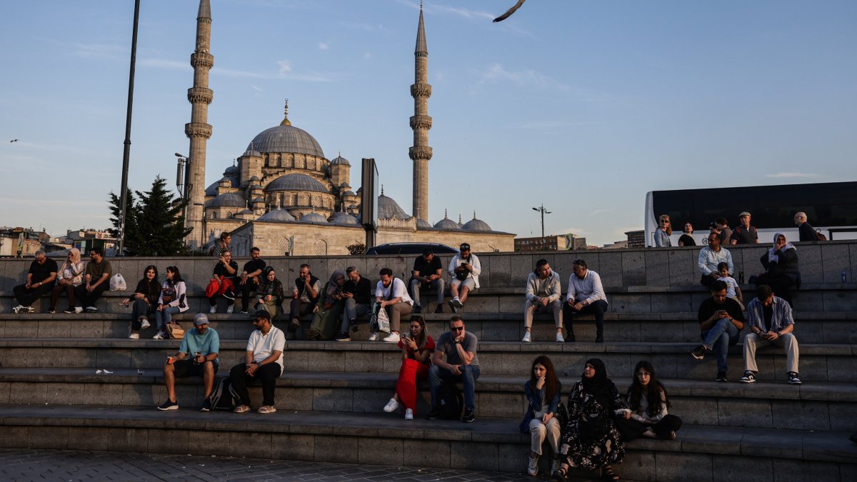 People sit in front of the Eminönü New Mosque during sunset in Istanbul, Türkiye, May 28, 2025. (EPA Photo)