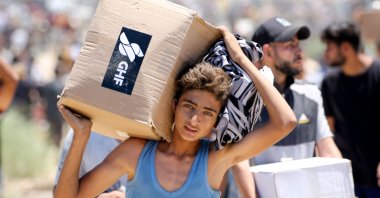 A boy carries a box of relief supplies from the Gaza Humanitarian Foundation (GHF), a private U.S.-backed aid group that has bypassed the longstanding U.N.-led system in the territory, as displaced Palestinians return from an aid distribution center, Gaza Strip, Palestine, May 29, 2025. (AFP Photo)