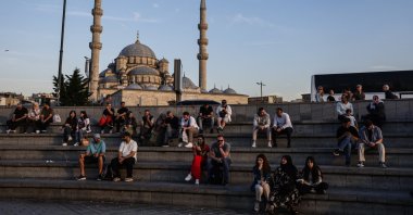 People sit in front of the Eminönü New Mosque during sunset in Istanbul, Türkiye, May 28, 2025. (EPA Photo)