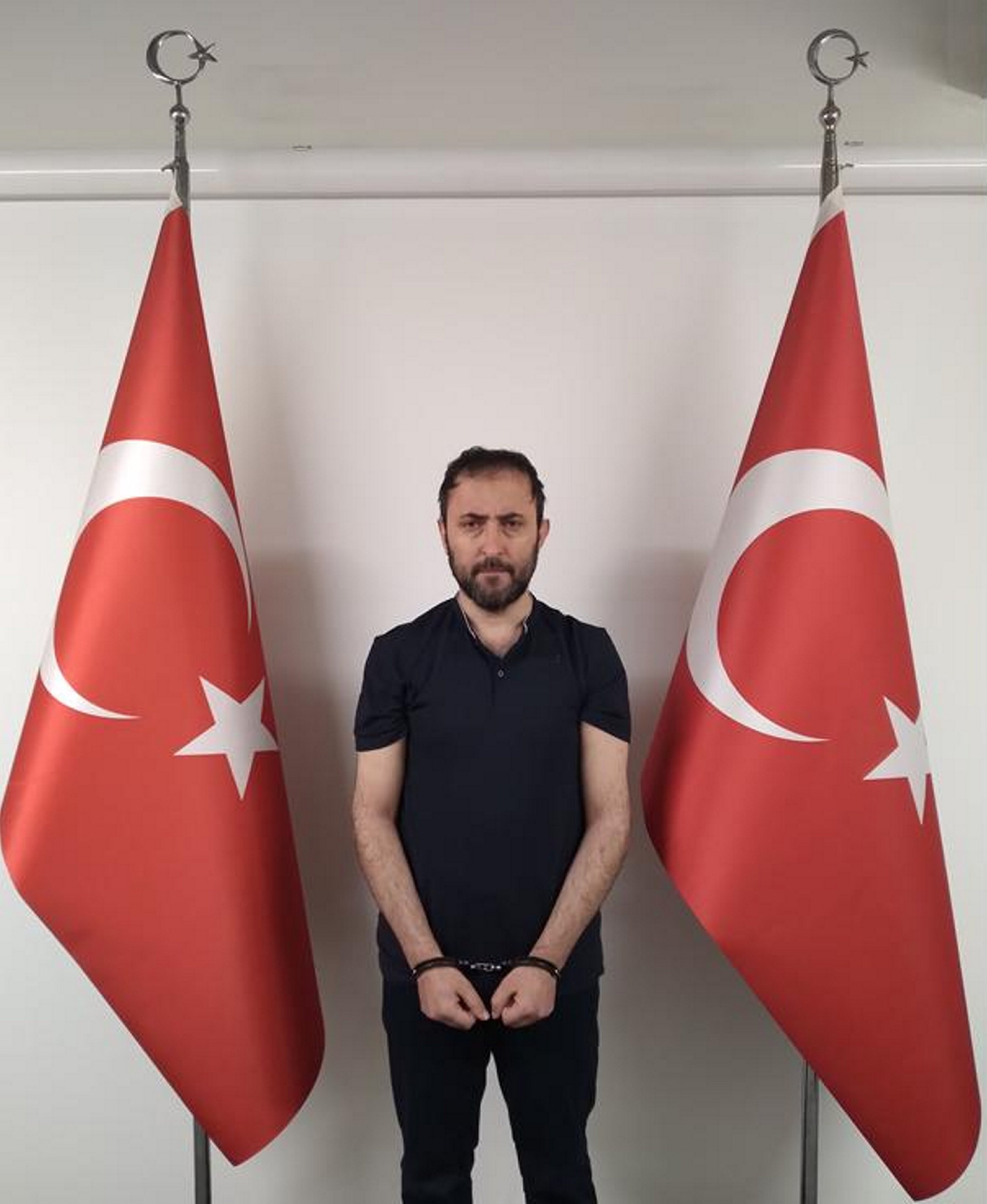 Tarihsiz bir fotoğraf, Özgür Altun'un yakalanmasından sonra açıklanmayan bir yerde iki Türk bayrağı arasında durduğunu gösteriyor. (AA fotoğrafı)