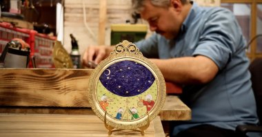 Artist Cebrail Çukurkaya works in his workshop alongside an astrolabe featuring miniature art, Bursa, northwestern Türkiye, May 31, 2025. (AA Photo)