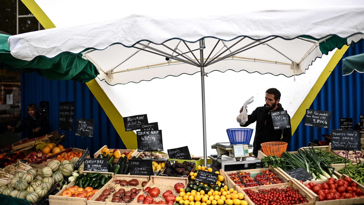 A vendor weighs vegetables at his stall set outside the central market, Royan, France, May 21, 2025. (AFP Photo)