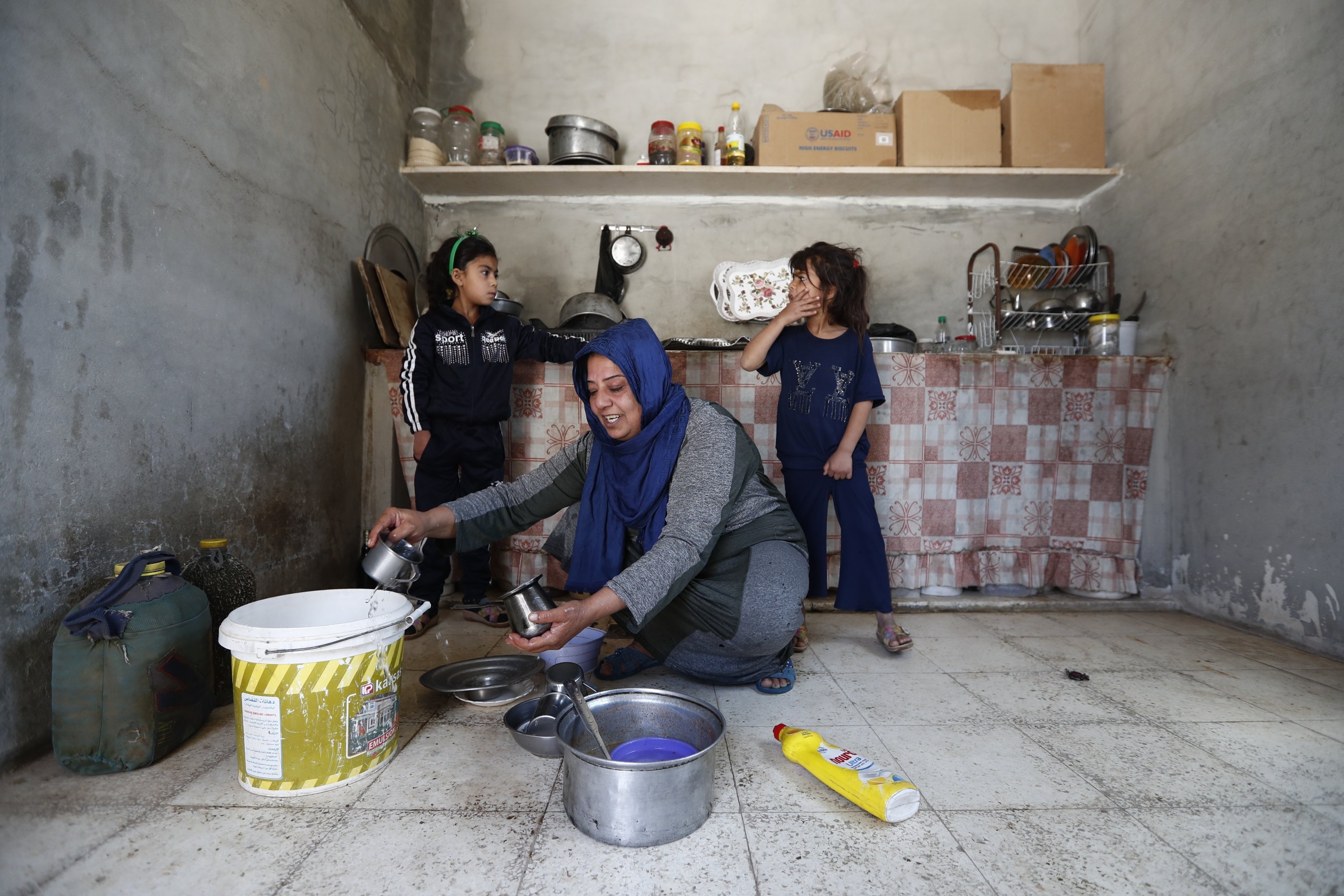 Yasmine al-Saleh cleans pots beside her daughters, Aya (L) and Nour, after she and her family returned to their home following nine years in a notorious displacement camp in the Syrian desert, al-Qaryatayn, Syria, June 3, 2025. (AP Photo)