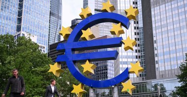 Pedestrians walk past the 'Euro Sculpture' by German artist Ottmar Hörl in front of the former seat of the European Central Bank (ECB) at the Eurotower, ahead a press conference on the Eurozone's monetary policy, in Frankfurt am Main, western Germany, June 5, 2025. (AFP Photo)